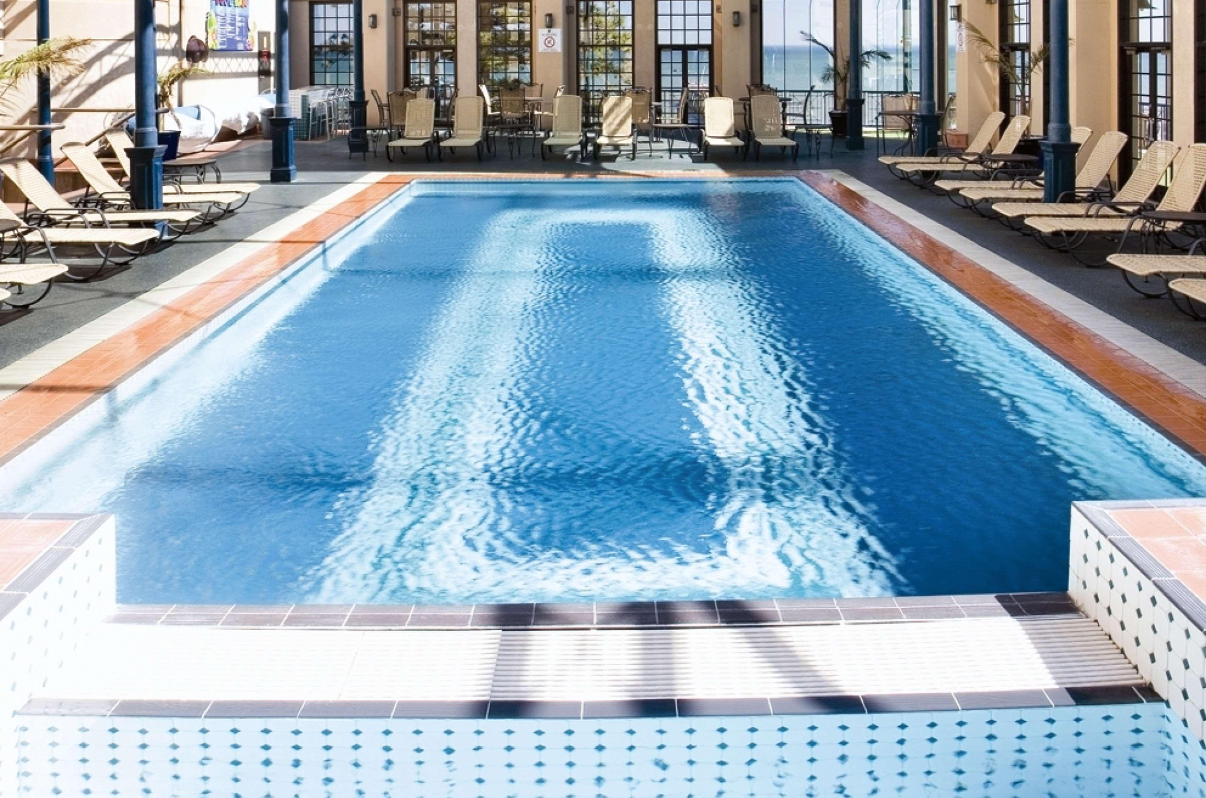 Stamford Grand Adelaide Hotel Glenelg Ngoại thất bức ảnh The photo shows an indoor swimming pool with a pristine blue surface. The pool is surrounded by a tiled deck and has lounge chairs lined up along the sides. Large windows allow natural light to flood the area, creating a bright and inviting atmospher
