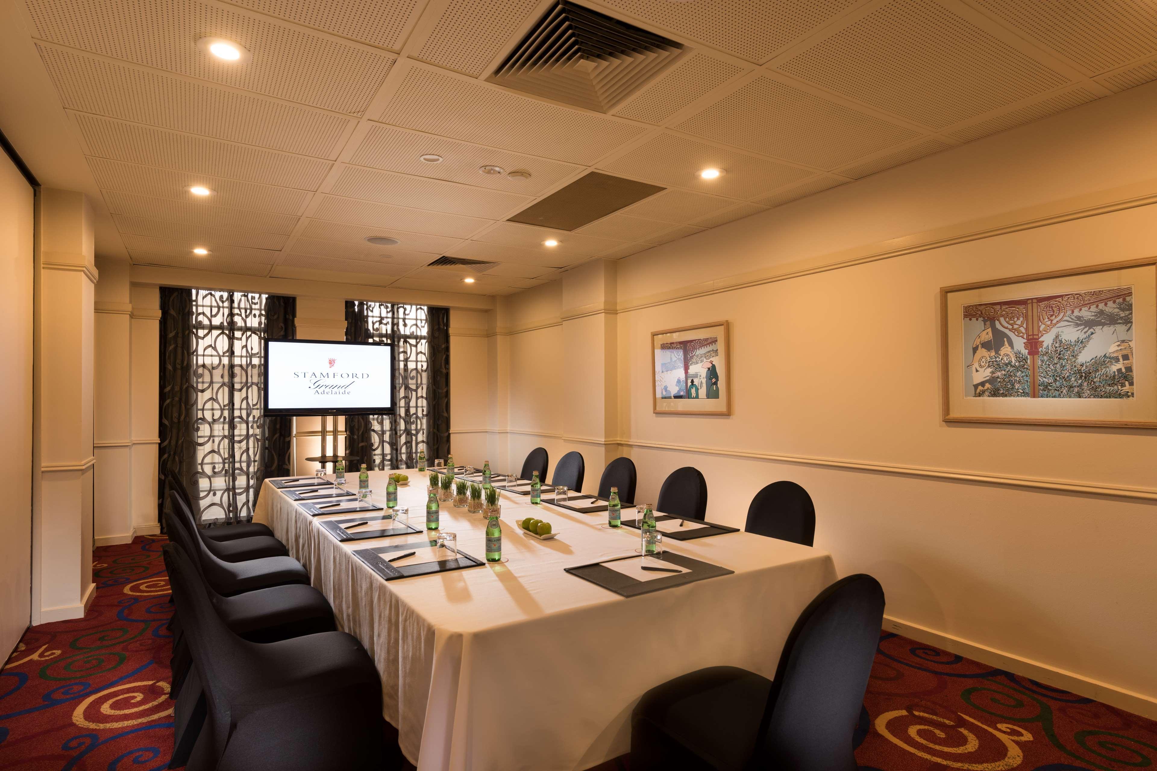 Stamford Grand Adelaide Hotel Glenelg Ngoại thất bức ảnh The photo shows a conference room with a long rectangular table set for a meeting. The table is covered with a white tablecloth and has several place settings, including notebooks, pens, and water bottles. There are black chairs around the table, and