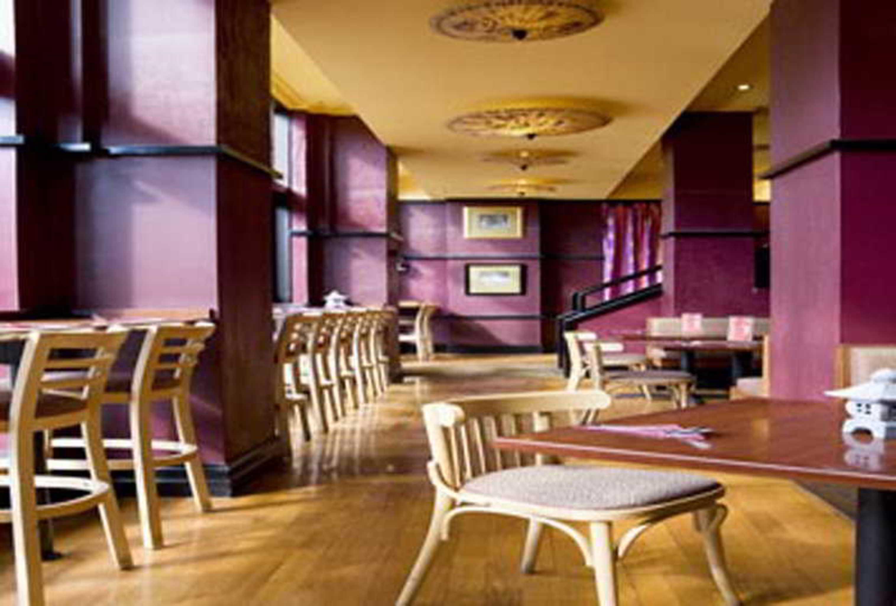 Stamford Grand Adelaide Hotel Glenelg Ngoại thất bức ảnh The photo shows the interior of a restaurant. It features wooden flooring and a warm color palette, primarily using shades of burgundy and gold. There are several wooden chairs arranged around tables, with the seating area appearing spacious and invi