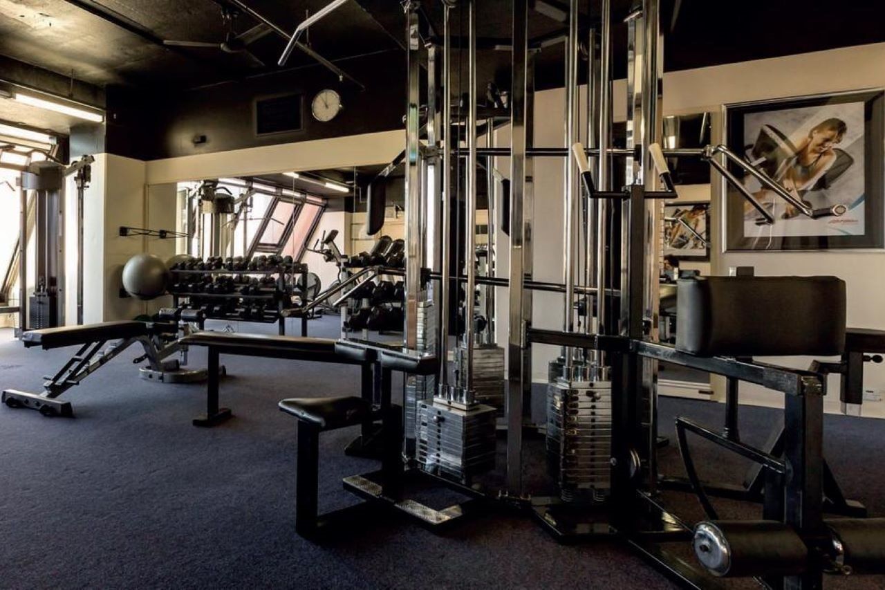 Stamford Grand Adelaide Hotel Glenelg Ngoại thất bức ảnh The photo shows a gym interior with various exercise equipment. In the foreground, there is a multi-station cable machine, which has several adjustable weights and pulleys for a variety of strength training exercises. To the side, there's a bench and